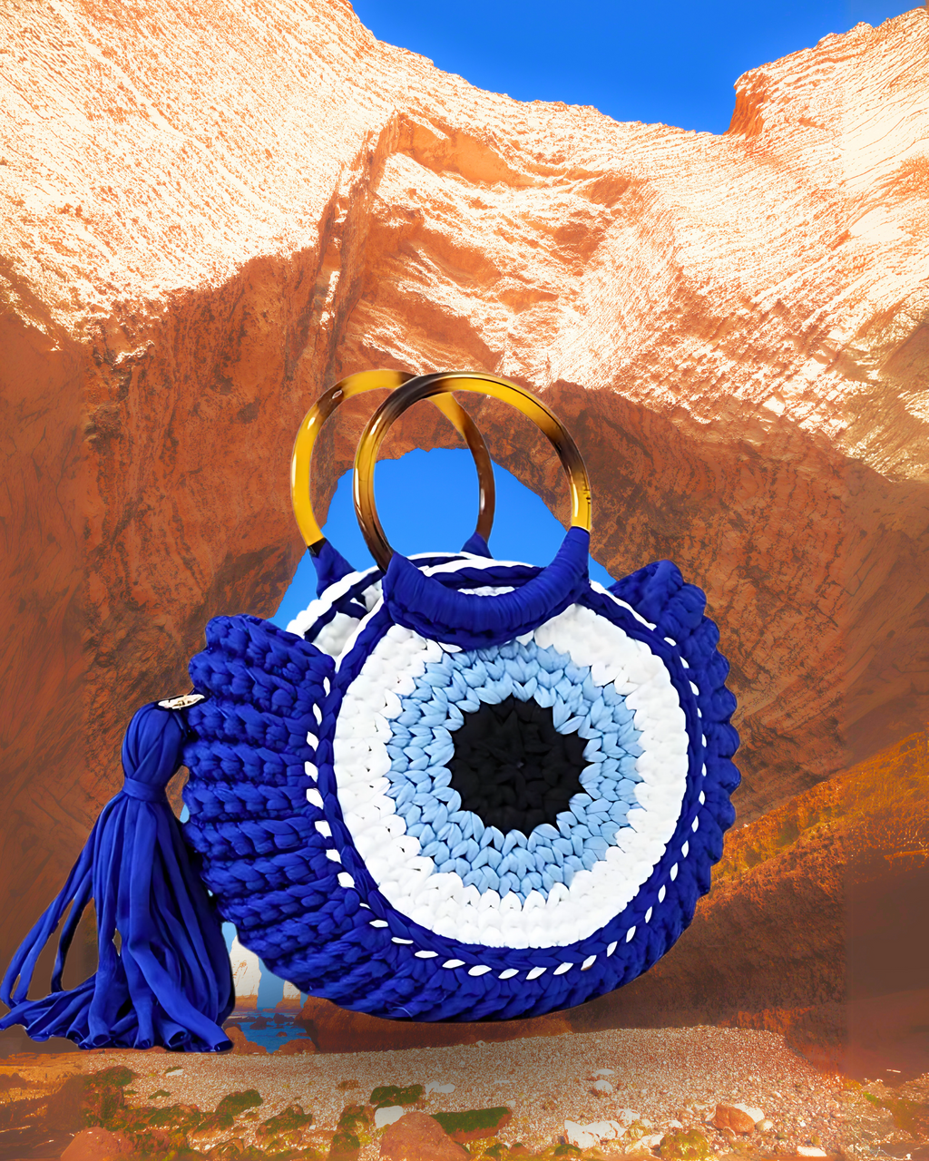 Round woven crochet handbag with layered fan-shaped black edges, evil eye design, and dual circular resin handles and a large matching side tassel. Blue color eye