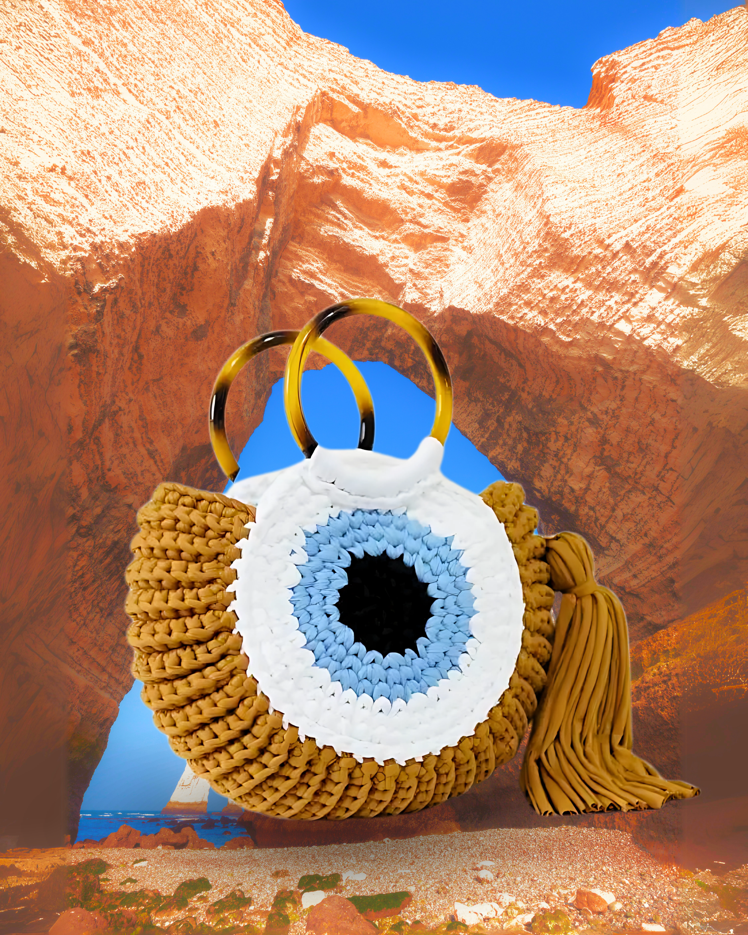 Round woven crochet handbag in mustard yellow with concentric blue, white, and black evil eye design, dual circular resin handles, and a large matching side tassel.
