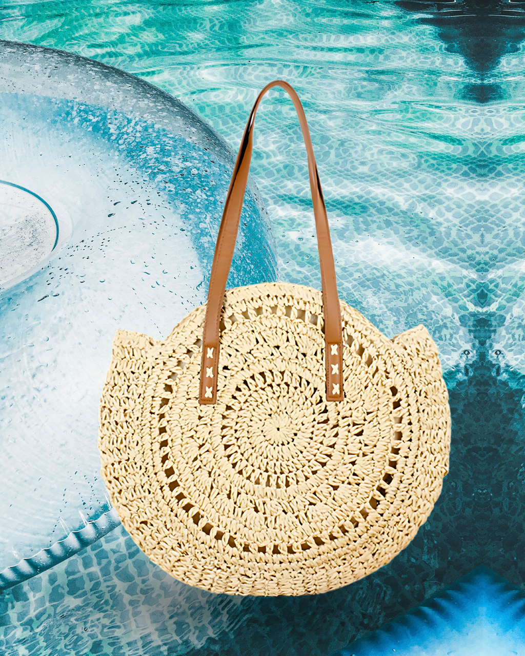 Round woven raffia tote bag with an open spiral crochet pattern and long brown leather shoulder straps for a casual summer style.