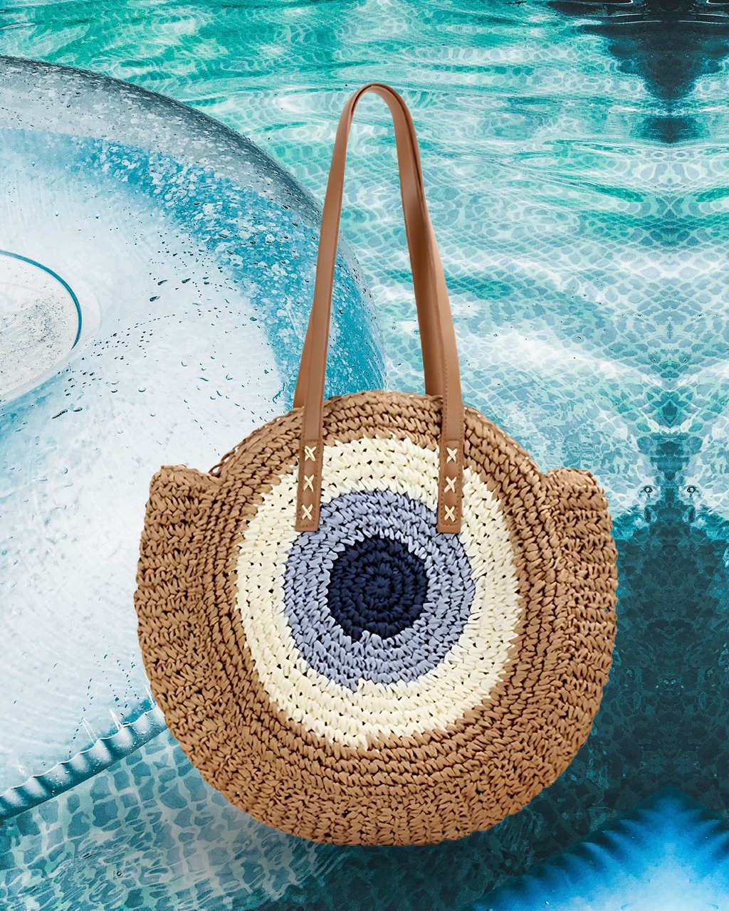 Round woven raffia tote bag with an evil eye design in navy, light blue, beige including long brown leather shoulder straps.