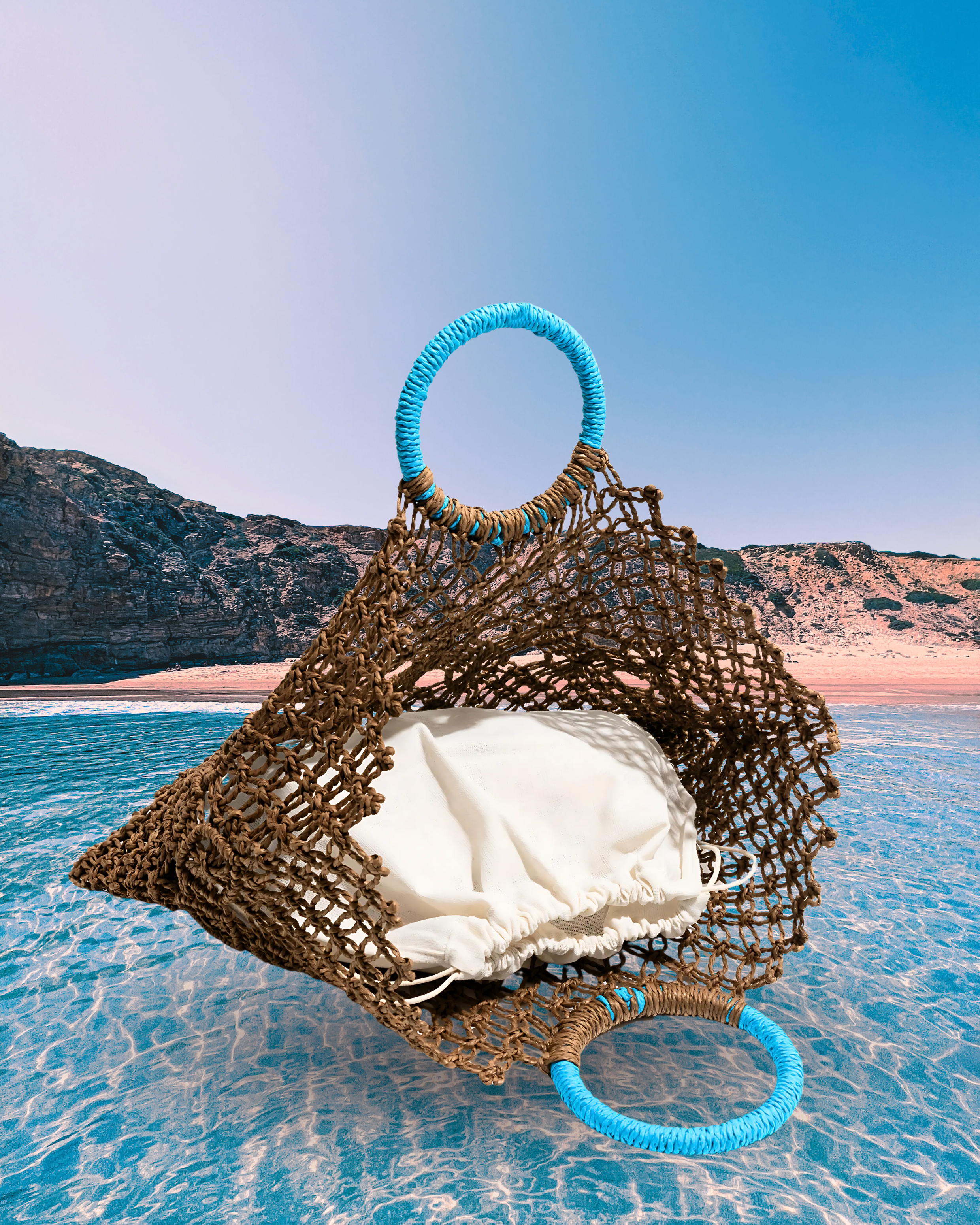 Rectangular woven straw net tote bag with diamond-patterned open weave, round turquoise-wrapped handles, and an inner fabric pouch