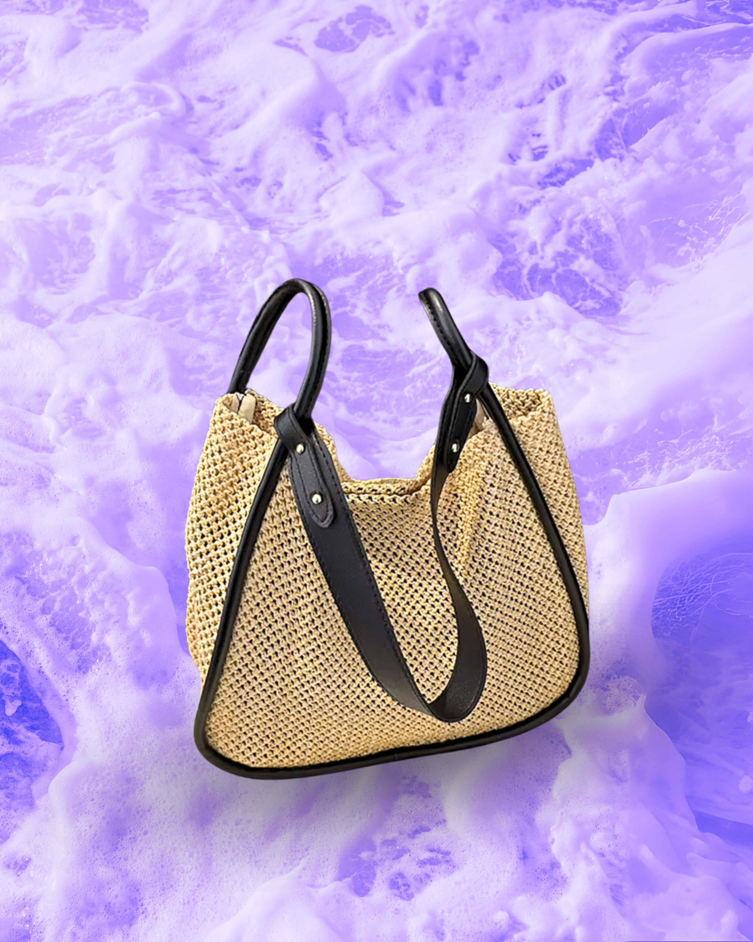 Soft rectangular woven raffia shoulder bag with a slouchy open-top design, long adjustable black leatherette strap, and black contrast trim framing the edges.