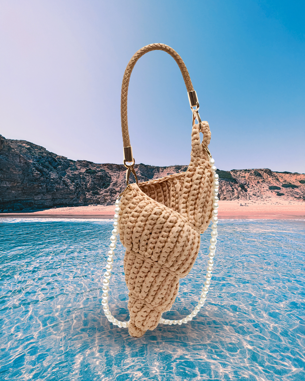 Handwoven beige handbag in a sculptural shell-inspired shape with a braided handle and detachable pearl chain strap for a playful, artistic design.