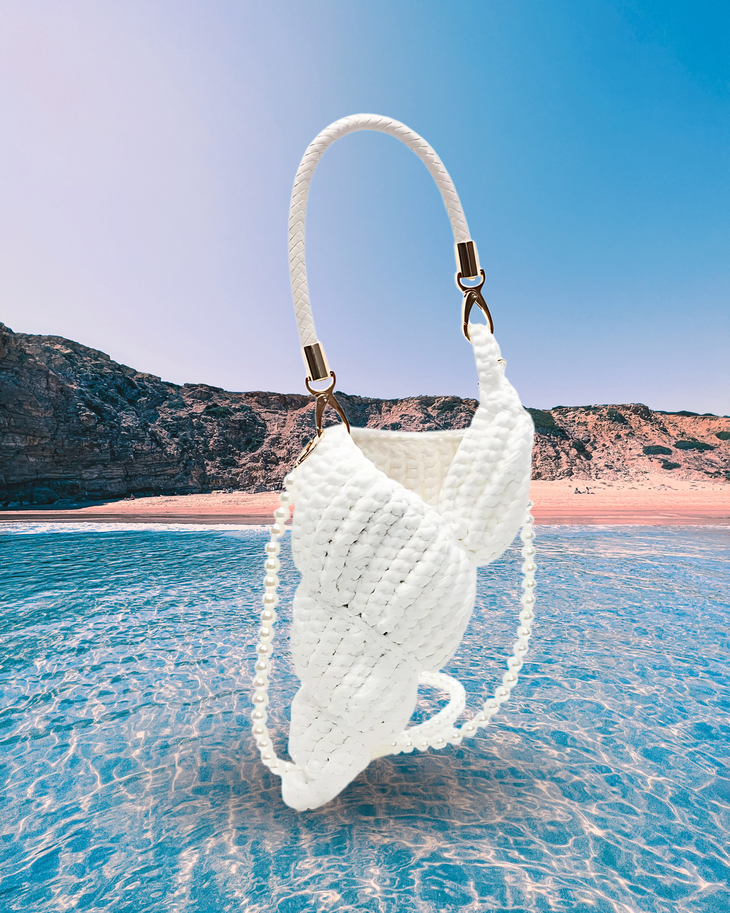 Handwoven white handbag in a sculptural shell-inspired shape with a braided handle and detachable pearl chain strap for a playful, artistic design.